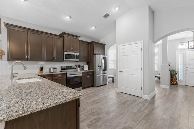 kitchen with visible vents, appliances with stainless steel finishes, arched walkways, and a sink