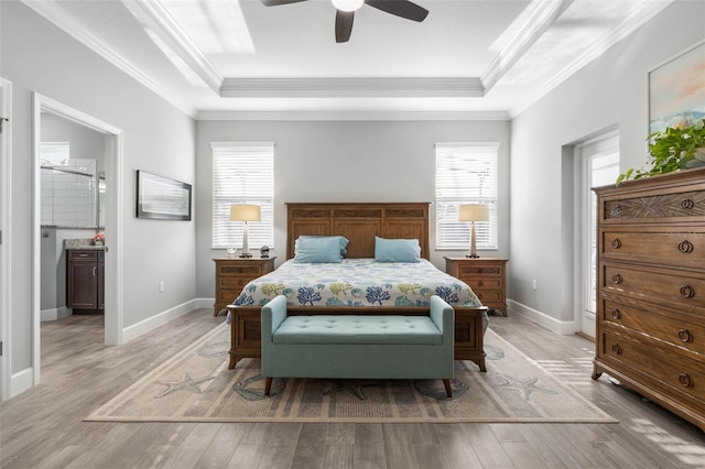 bedroom featuring ornamental molding, light wood finished floors, and a raised ceiling