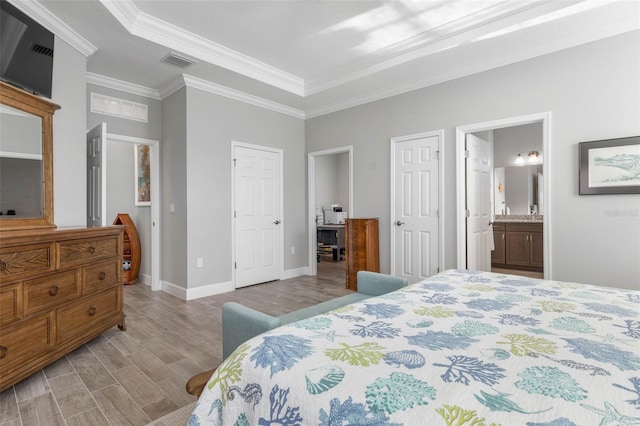 bedroom with visible vents, baseboards, ornamental molding, light wood-type flooring, and ensuite bath