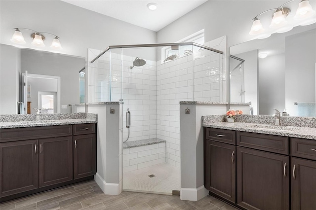 bathroom with a stall shower, two vanities, a sink, and wood tiled floor