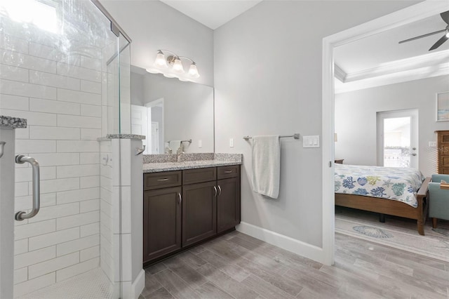 full bath with ensuite bathroom, wood finish floors, a ceiling fan, baseboards, and a stall shower