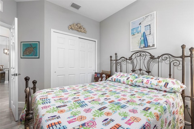 bedroom featuring baseboards, visible vents, a closet, and wood finished floors