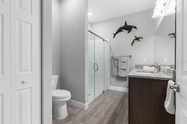 full bathroom featuring toilet, wood finish floors, vanity, baseboards, and a stall shower