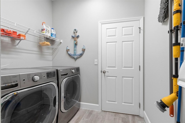 washroom with light wood-type flooring, washer and dryer, laundry area, and baseboards