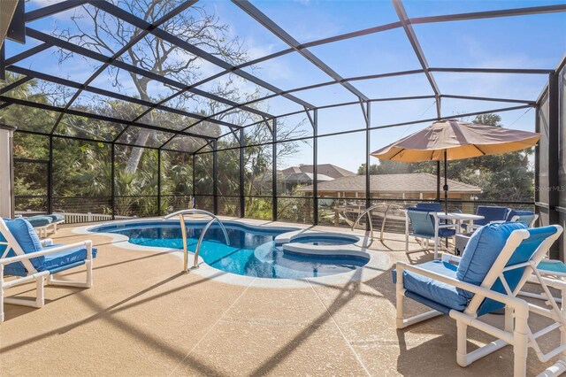 view of swimming pool featuring glass enclosure, a patio area, and a pool with connected hot tub