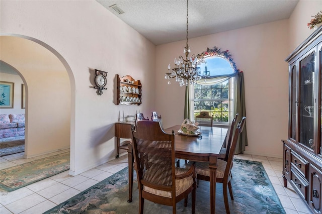 dining space with arched walkways, light tile patterned floors, visible vents, a textured ceiling, and a chandelier