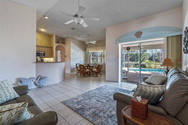 living area with a ceiling fan, visible vents, light tile patterned flooring, and a textured ceiling