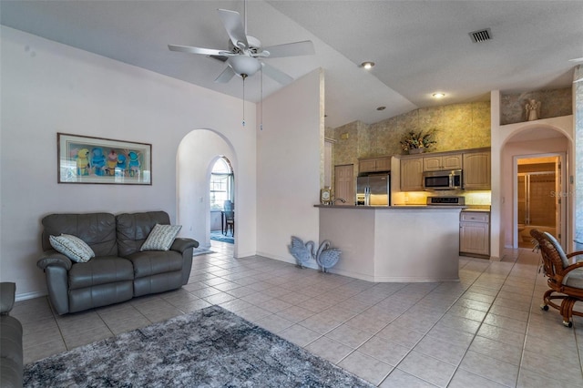 interior space with light tile patterned floors, visible vents, arched walkways, ceiling fan, and high vaulted ceiling