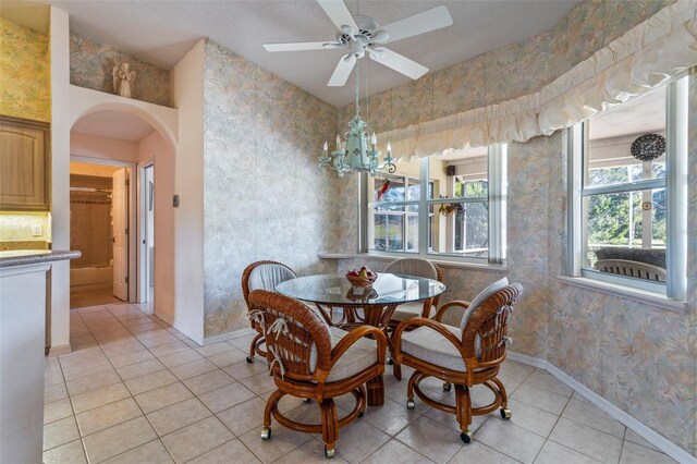 dining space with arched walkways, light tile patterned flooring, baseboards, and wallpapered walls