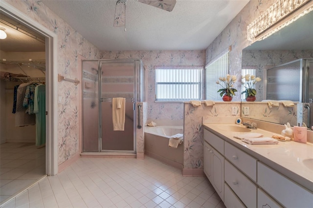 full bathroom featuring wallpapered walls, a textured ceiling, a sink, and a stall shower