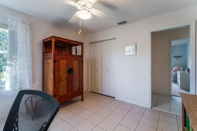 bedroom featuring light tile patterned floors, visible vents, a ceiling fan, a textured ceiling, and a closet