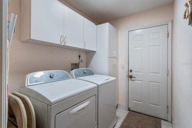 washroom with cabinet space, washing machine and clothes dryer, and light tile patterned floors