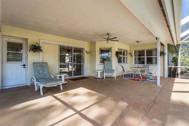 view of patio featuring ceiling fan and glass enclosure