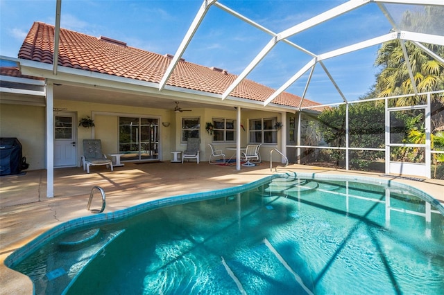 pool with glass enclosure, a patio, and ceiling fan