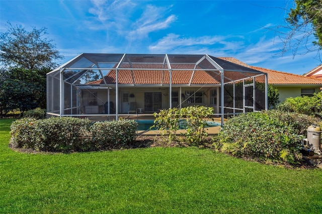 rear view of house with glass enclosure, a tile roof, stucco siding, and a yard