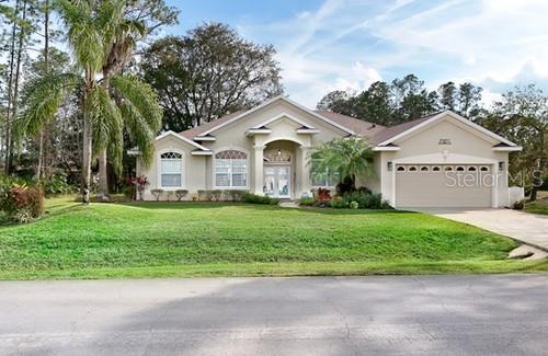 single story home with a garage, concrete driveway, french doors, a front lawn, and stucco siding