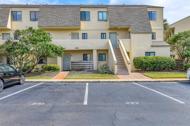 view of property with uncovered parking and stairway