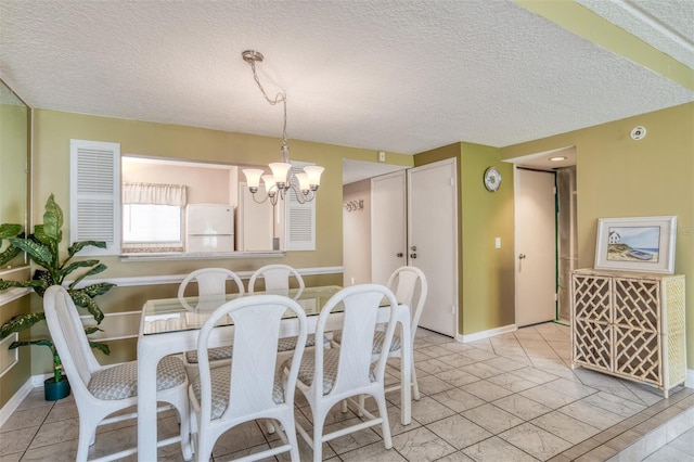 dining space featuring a notable chandelier, a textured ceiling, and baseboards