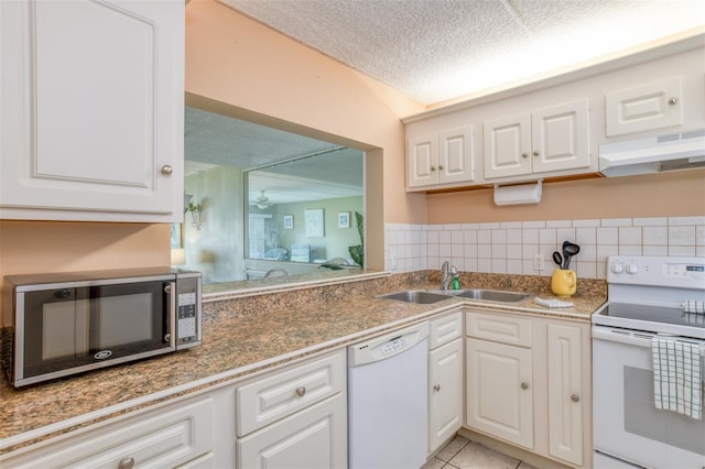 kitchen featuring white appliances, white cabinets, a textured ceiling, under cabinet range hood, and a sink