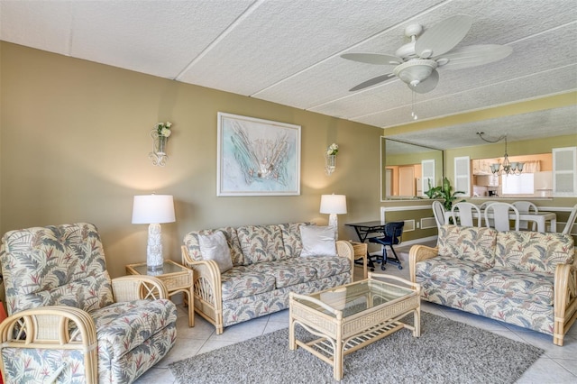 living area with ceiling fan with notable chandelier, a textured ceiling, and tile patterned flooring