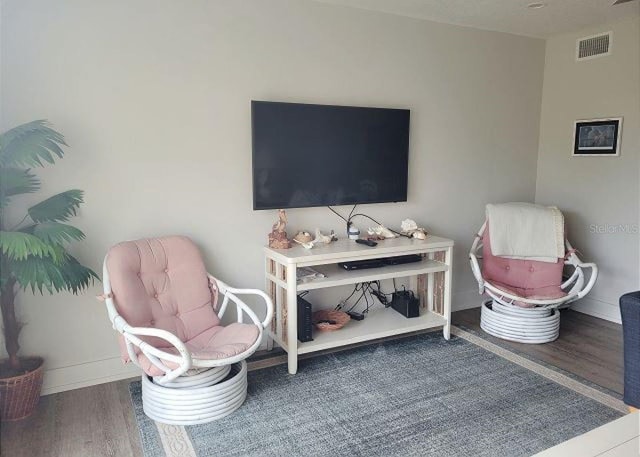 living area with baseboards, visible vents, and wood finished floors