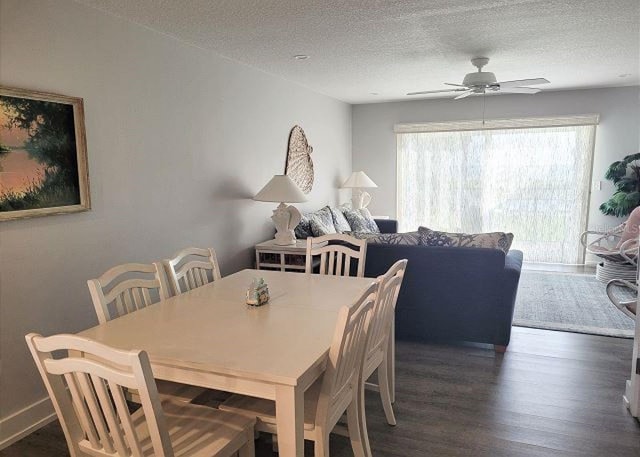 dining area featuring dark wood-style floors, baseboards, a ceiling fan, and a textured ceiling