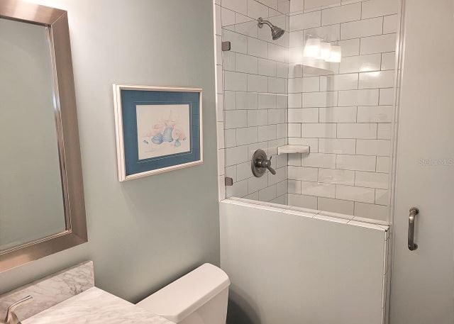 full bathroom with a tile shower and toilet