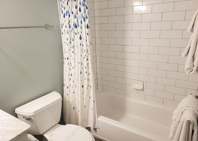 bathroom with shower / bathtub combination with curtain and toilet