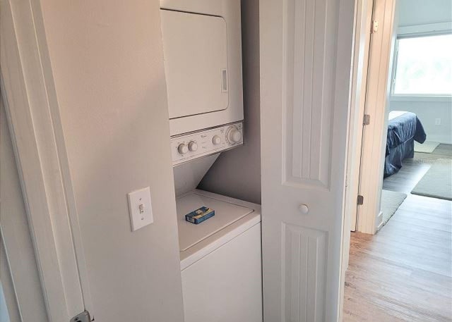 washroom featuring laundry area, light wood-style flooring, and stacked washing maching and dryer