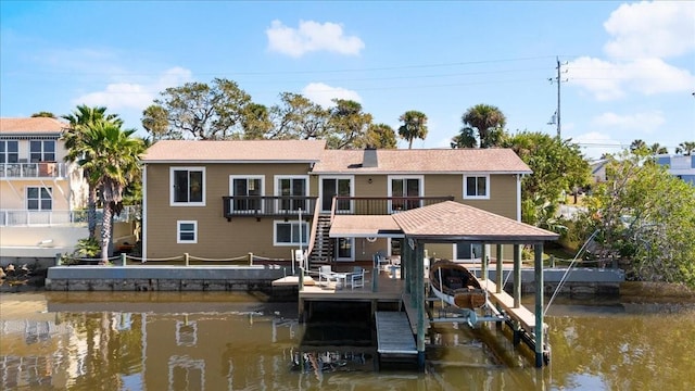 rear view of house featuring boat lift, a chimney, stairs, a deck with water view, and a carport