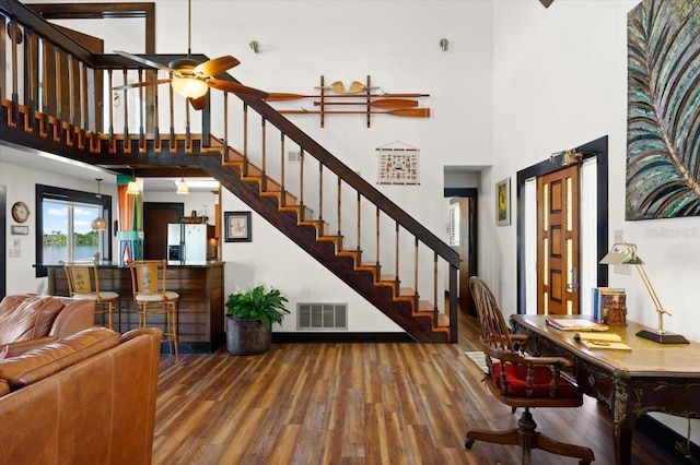 interior space with a high ceiling, wood finished floors, visible vents, and a ceiling fan