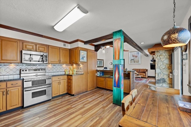 kitchen with open floor plan, appliances with stainless steel finishes, light wood-type flooring, tasteful backsplash, and dark countertops