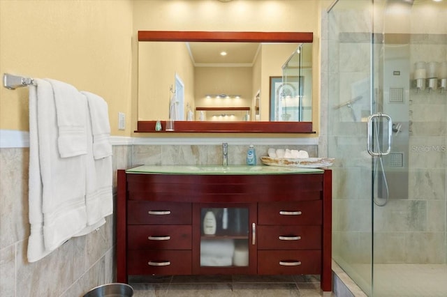 bathroom with a shower stall, crown molding, tile walls, and vanity