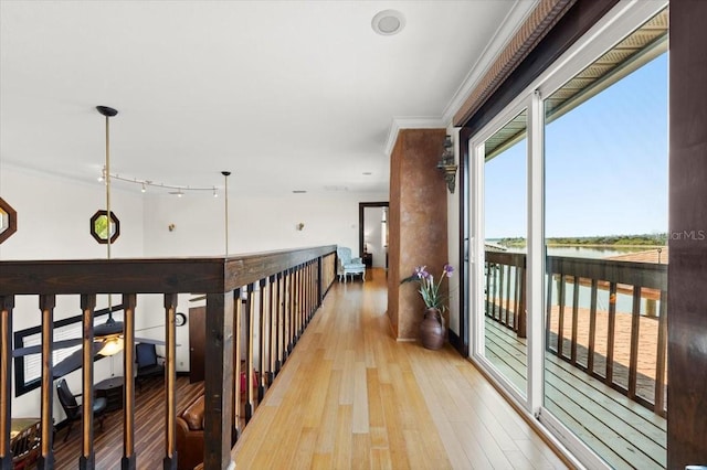 hall with ornamental molding, light wood finished floors, and a water view