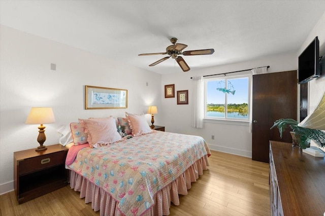 bedroom with light wood-type flooring, baseboards, and a ceiling fan