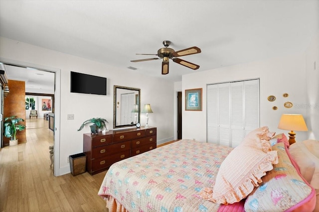 bedroom featuring light wood-type flooring, ceiling fan, visible vents, and a closet