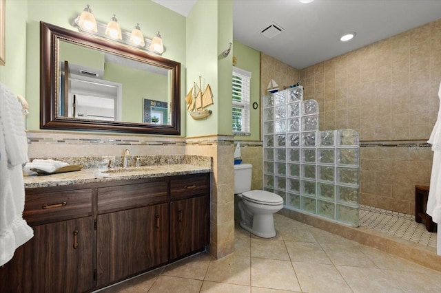 bathroom featuring tile patterned flooring, tile walls, vanity, and a walk in shower