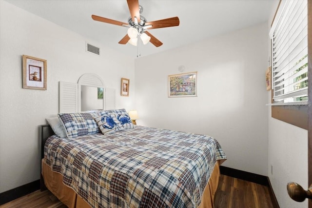 bedroom featuring a ceiling fan, baseboards, visible vents, and wood finished floors