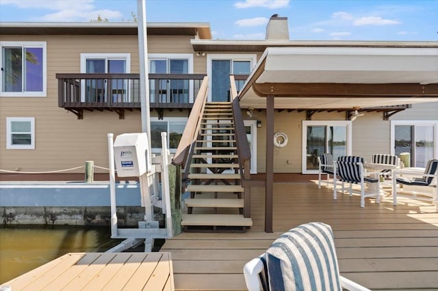 back of house with stairs, a chimney, and a water view