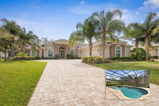 mediterranean / spanish house featuring decorative driveway, stucco siding, a front yard, a garage, and an outdoor pool