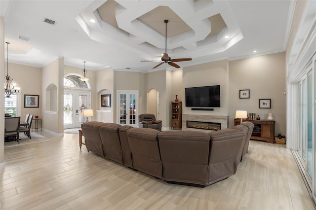 living area with french doors, a glass covered fireplace, a towering ceiling, and crown molding