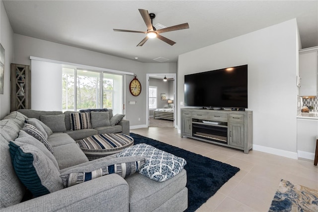 living area featuring ceiling fan, baseboards, and light tile patterned floors