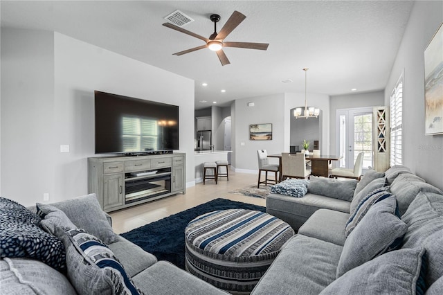 living area featuring light tile patterned floors, recessed lighting, ceiling fan with notable chandelier, visible vents, and baseboards