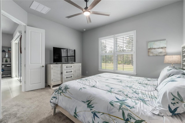 bedroom with light tile patterned floors, a ceiling fan, visible vents, and light colored carpet