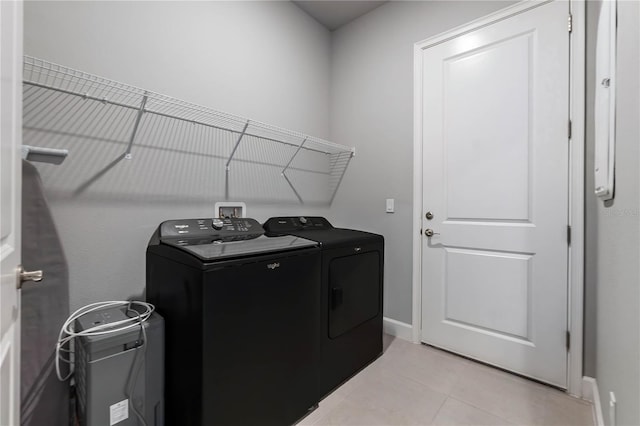 washroom with laundry area, baseboards, washing machine and clothes dryer, and light tile patterned floors