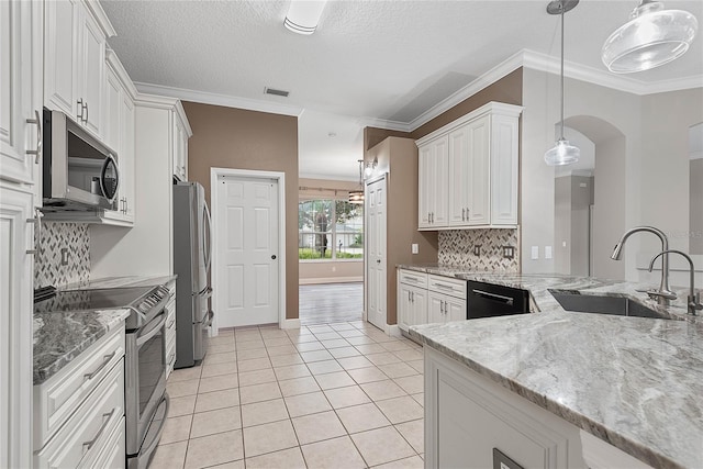 kitchen with a sink, stainless steel appliances, white cabinets, crown molding, and light tile patterned floors