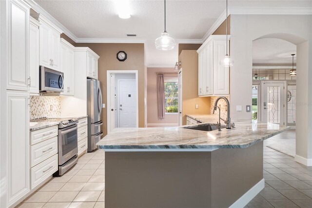 kitchen with a sink, stainless steel appliances, ornamental molding, and light tile patterned floors