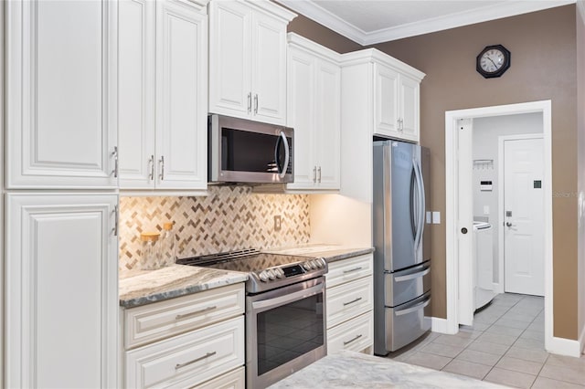 kitchen with washer / dryer, light tile patterned flooring, stainless steel appliances, white cabinets, and crown molding