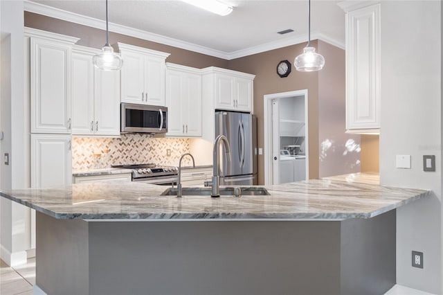 kitchen with light stone counters, separate washer and dryer, a sink, stainless steel appliances, and white cabinetry