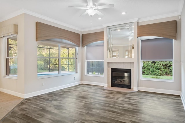 unfurnished living room featuring baseboards, wood finished floors, ornamental molding, and a tiled fireplace